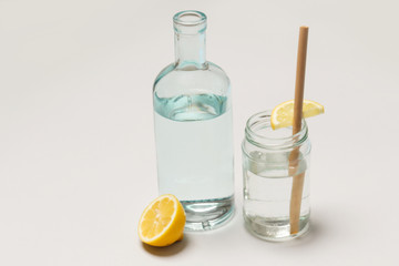 Bamboo straw in a glass of lemon water on the grey background, Reusable bamboo straws as an alternative for single-use plastic straws, healthy and sustainable lifestyle concept