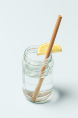Bamboo straw in a glass of lemon water on the blue background, Reusable bamboo straws as an alternative for single-use plastic straws, healthy and sustainable lifestyle concept