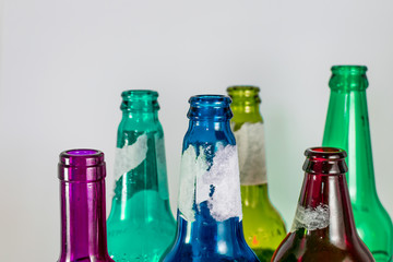 Image of the bottleneck of empty colored beer and wine glass bottles on a white background. Green, yellow, pink and blue colours. Reuse, acoholism, medicine, recycle and party concept.