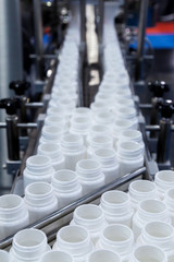 Obraz premium white plastic bottle on the production line of the conveyor at filling machine in the factory. selective focus.