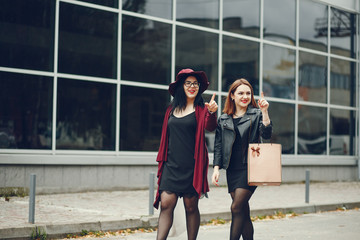 two beautiful and stylish girlfriends walking around the summer city with packages and shopping