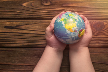 the layout of the earth in his hands on the background of a wooden table. outlook.