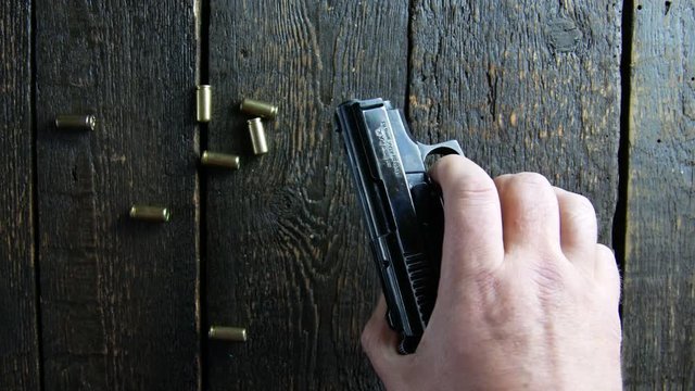 Hand puts a gun on a wooden background