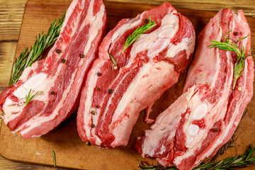 Raw pork ribs with spices and rosemary on wooden table. Top view
