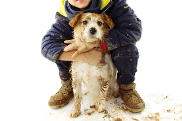 FUNNY DIRTY DOG AND CHILD. JACK RUSSELL PUPPY AND BOY WEARING BOOTS AFTER PLAY IN A MUD PUDDLE....