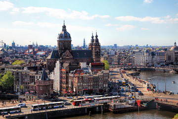 Fototapeta premium Amsterdam cityscape with Grand Amarath hotel. City streets with active tram and car traffic along the canal. Panoramic distance view. 