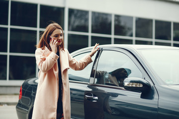 young and elegant business woman standing near car and use the phone
