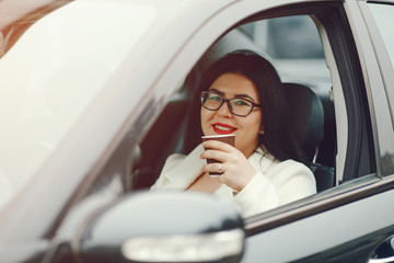 young and elegant business woman sitting in a car and drinking a coffee