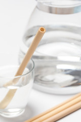 Bamboo straw in a glass of water on the grey background, Reusable bamboo straws as an alternative for single-use plastic straws, healthy and sustainable lifestyle concept