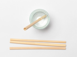 Bamboo straw in a glass of  water on the grey background, Reusable bamboo straws as an alternative for single-use plastic straws, healthy and sustainable lifestyle concept