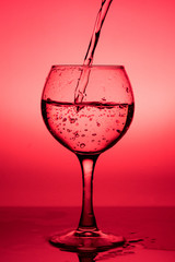 Flowing  liquid (wine) in a glass on a red background