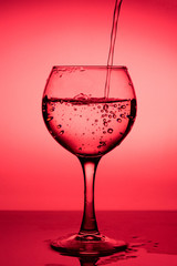 Flowing  liquid (wine) in a glass on a red background