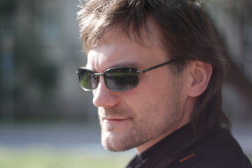 a man in a black jacket and sunglasses in the park