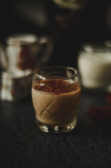 Irish cream liqueur in a glass with cinnamon on dark background
