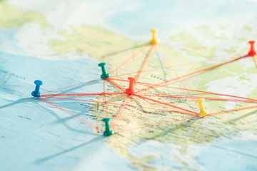 Selective focus of push pins and strings on world map - obrazy, fototapety, plakaty