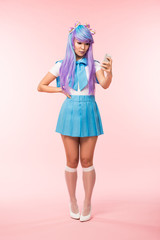 Full length view of asian anime girl holding smartphone on pink