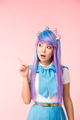 Pensive asian anime girl in wig showing idea sign on pink