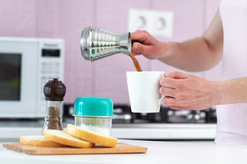 Woman pouring hot tasty turkish coffee from cezve for breakfast at kitchen in morning