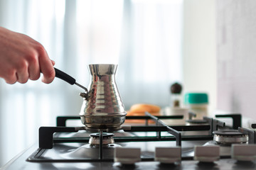 Preparing hot tasty turkish coffee from cezve on stove for coffee break at kitchen at home.