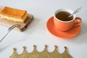 Orange tompouce, traditional Dutch treat with pudding and frosting on national holiday Kings Day (April 27th), in The Netherlands. With cup of tea and crown