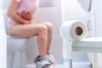 Ill, unwell woman suffering from diarrhea, constipation and cystitis at toilet. Stomach pain during PMS. Health care and pain concept - obrazy, fototapety, plakaty