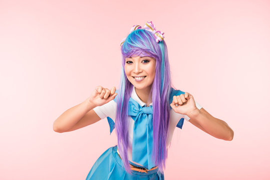 Smiling asian anime girl in wig posing isolated on pink