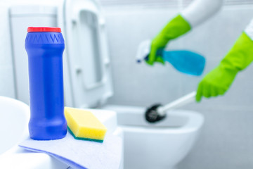 Housewife in rubber gloves cleaning and disinfecting toilet using cleaning products and a brush. Cleaning service