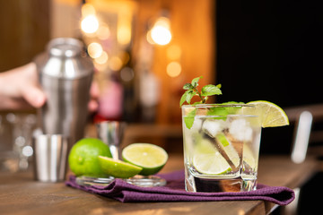 Lime cocktail with mint and ice on the background of the bar.