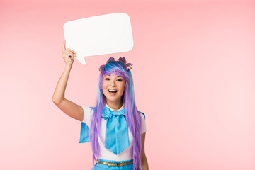 Excited asian anime girl in purple wig holding speech bubble on pink