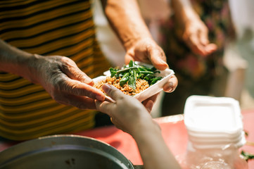 Volunteers provide food for beggars : Concepts Feeding and help : The hands of the rich give food...