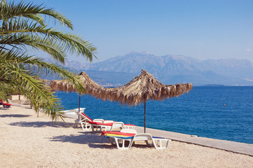 Summer beach vacation.  Sunny Mediterranean landscape with beach umbrellas. Montenegro, Adriatic Sea,  Bay of Kotor, Herceg Novi