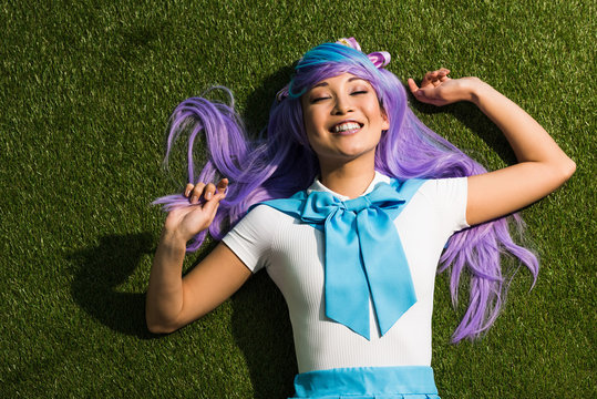 Laughing Anime Girl In Purple Wig Lying On Grass With Closed Eyes