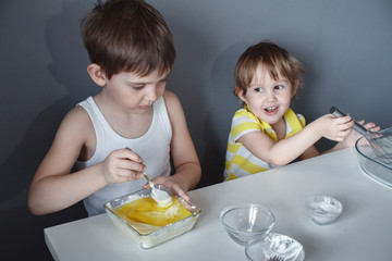 The preparation of the dessert. Two little kids are having fun making shortbread cookies, sitting...