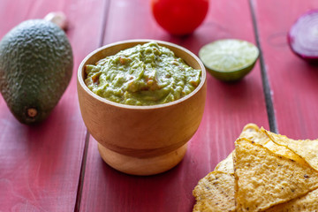 Guacamole and chips nachos. Red background. Mexican cuisine.