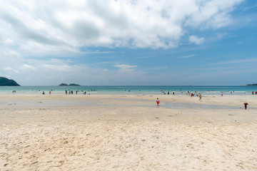 People take a dip in the sea and stroll on the white sand.