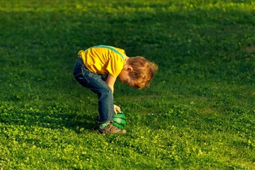 Boy on green grass lawn in summer park,  happy.