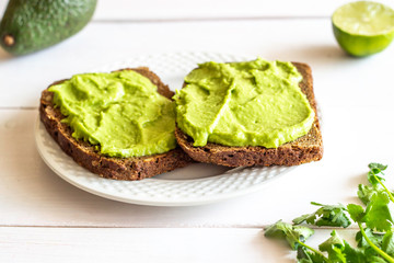 Sandwiches with avocado on the white wooden background.