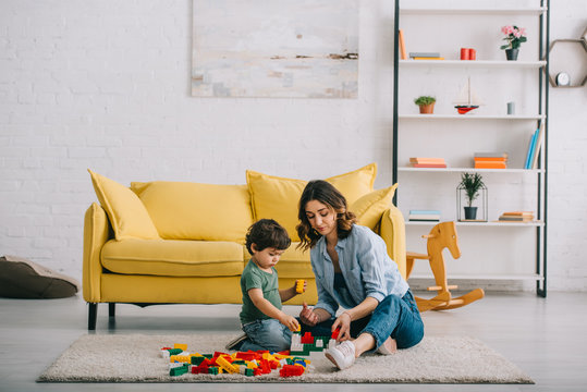 Mother and son playing with Bricks on carpet in living room