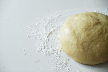 Raw dough lying on the table on a white background. A piece of dough for bread baking. Pasta dough. Shortbread