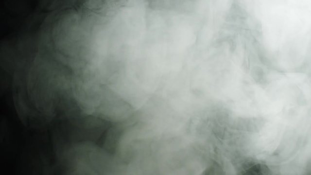 Billowing smoke on black background. Stock footage. Thin streams of white smoke clouds spreading on black isolated background