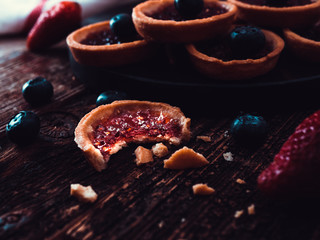 Fresh homemade strawberries tarts on wooden background with a bite