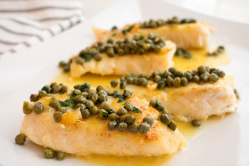 Seared Grouper Fillets with Lemon-Caper Butter: Four whitefish fillets drizzled with lemon-butter sauce and topped with capers and chopped parsley
