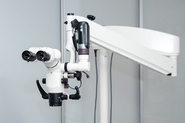 Dental microscope. Modern dentistry on the background. Medical equipment. Operating microscope with rotary double binocular in white cabinet working room