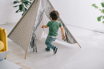 child in jeans running to grey wigwam in living room © LIGHTFIELD STUDIOS