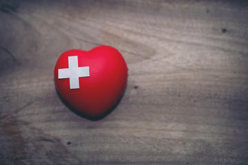 Cushioned Plaster Strip Medical Patch First aid glued on a red heart on a wooden floor. The concept of cardiovascular health care, heart disease and organ donors for life, providing a charity campaign