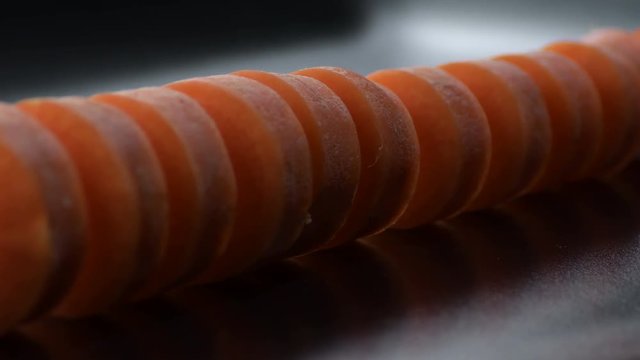 Raw carrot cut gyrating on a black tray with black background. Daucus carota