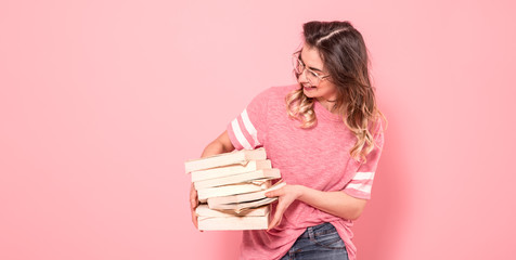 Portrait of a girl with a stack of books on a pink background