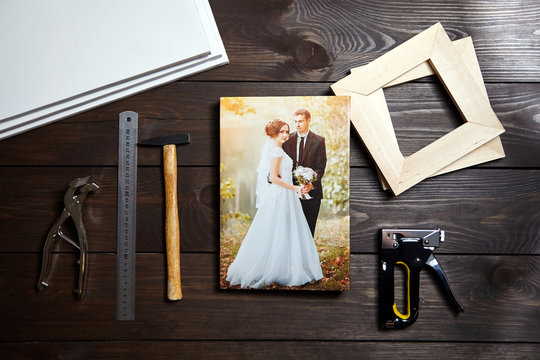 Photo of a wedding couple printed on canvas. Photography on a wooden table. Stretching canvas tools, staple gun, stretcher bars
