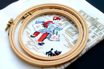 embroidery on fabric, embroidery hoop, flowers, pins on a dark background, needlework concept