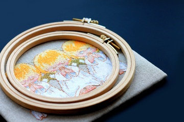 embroidery on fabric, embroidery hoop, flowers, pins on a dark background, needlework concept